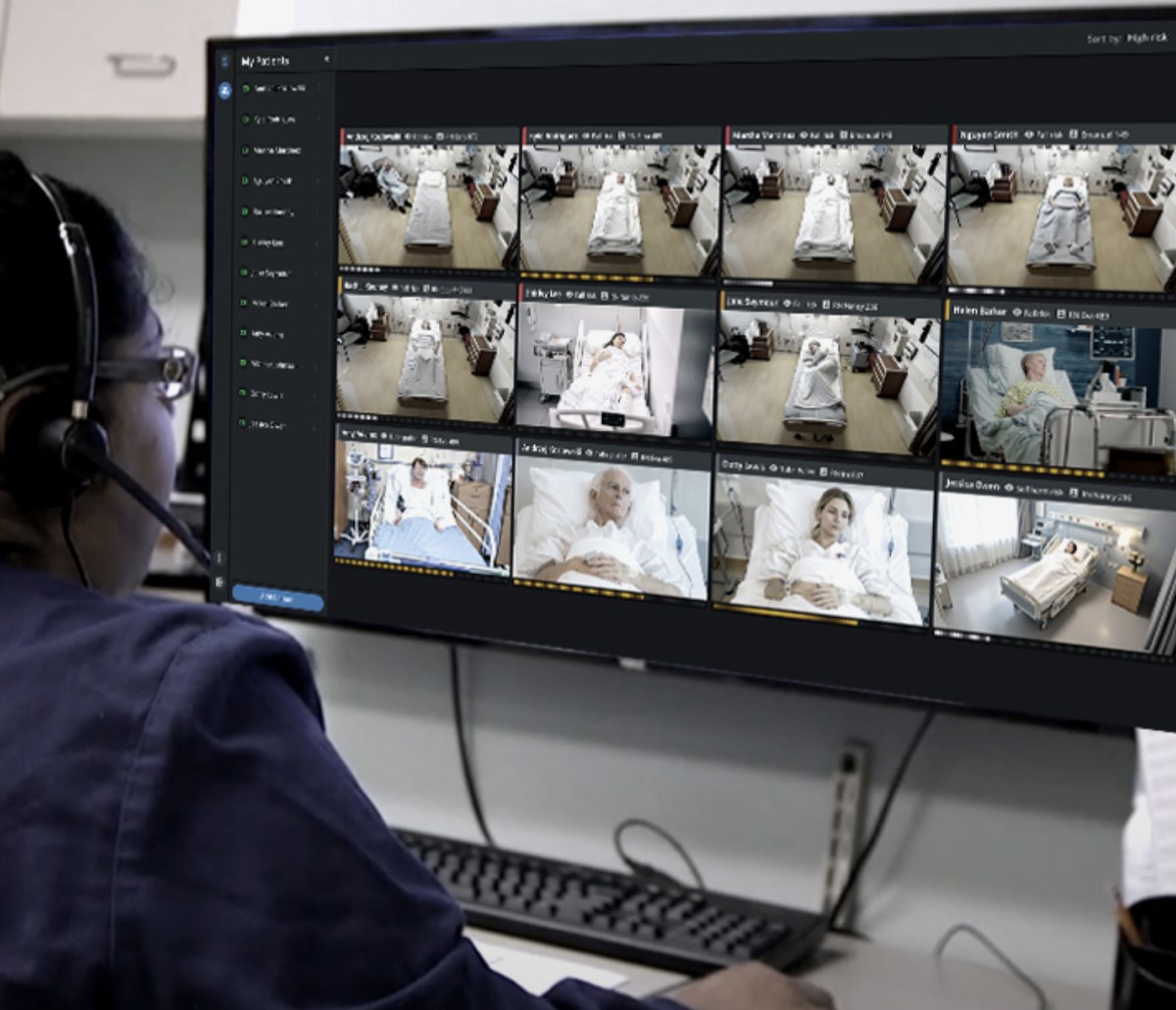 A remote technician watching a twelve-patient video grid on a wide monitor